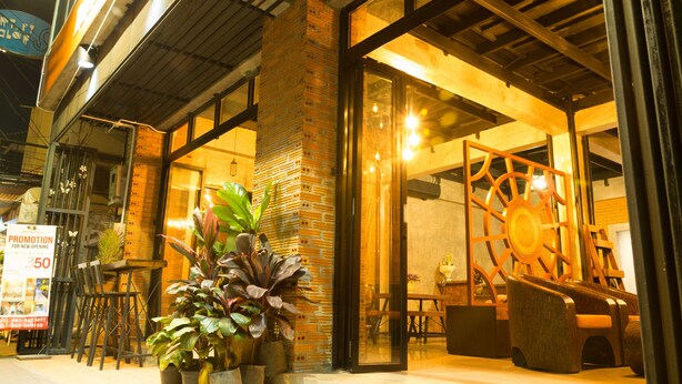 A restaurant with outdoor seating, a brick wall, and a large wooden wheel decoration. - Iris hostel (Chiang Mai)