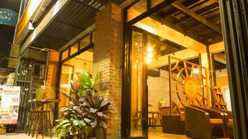 A restaurant with outdoor seating, a brick wall, and a large wooden wheel decoration.