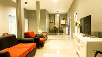 A modern living room with a sofa, ottoman, and a TV on a stand.