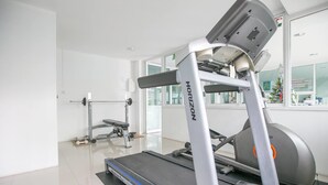 A gym with a treadmill, weight bench, and exercise equipment. - De Resto (Hat Yai)