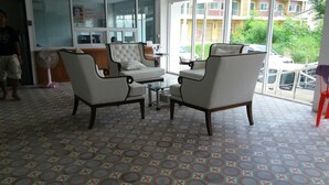 A room with two armchairs, a small table, and a fan. The floor has a patterned tile design. - De Resto (Hat Yai)