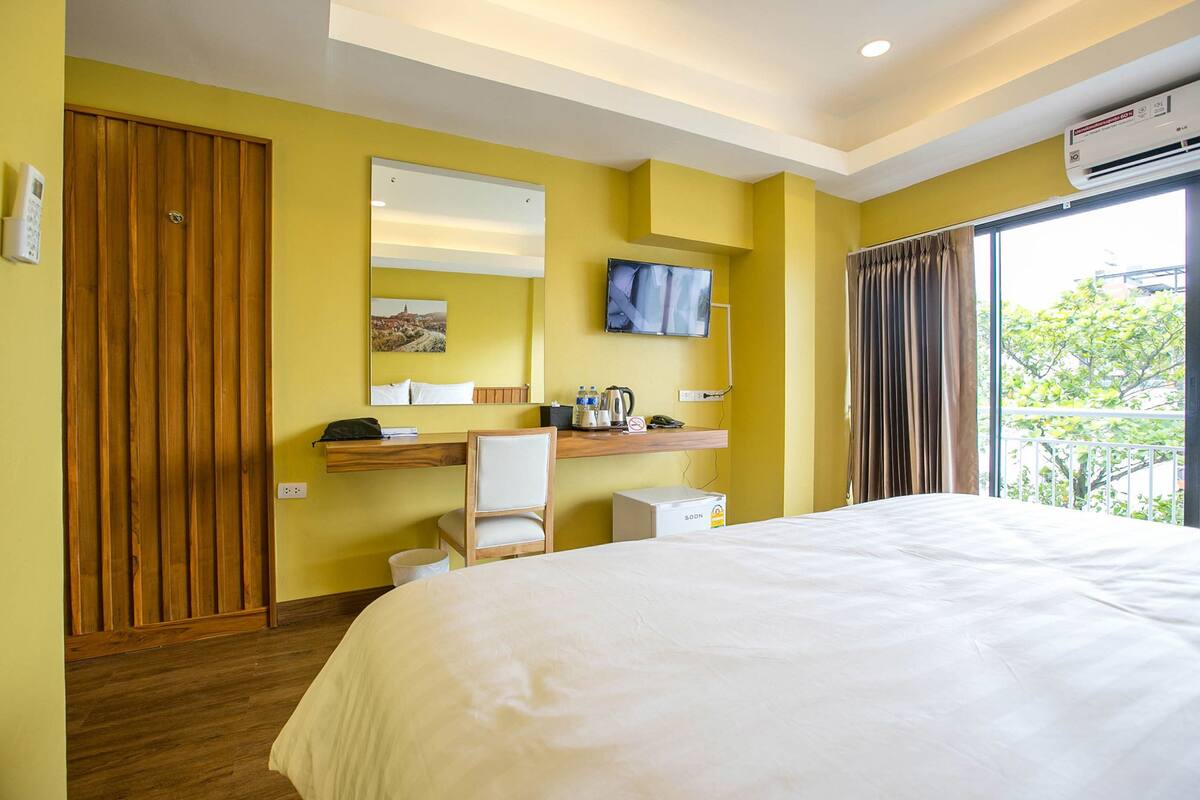 A hotel room with a bed, a desk, a chair, a television, and a window with curtains.