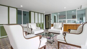 A lobby with white leather chairs, a glass coffee table, and a reception desk. - De Resto (Hat Yai)