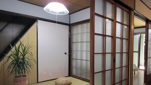 A traditional Japanese room with tatami flooring, a shoji screen door, and a potted plant. - Secret Garden Kyoto (Kyoto)