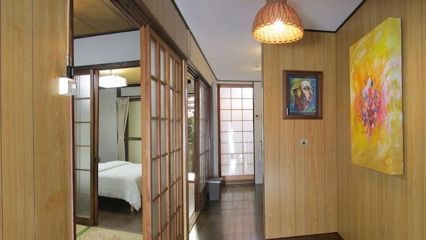 A hallway with wooden walls, a bed in the background, and a painting on the wall. - Secret Garden Kyoto (Kyoto)