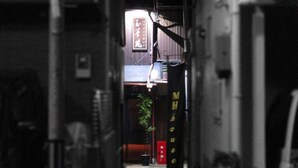 A narrow alleyway with a building entrance, a sign with Japanese characters, and a hanging light fixture. - Secret Garden Kyoto (Kyoto)