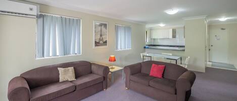 A modern living room with two sofas, a small table, and a kitchen in the background.