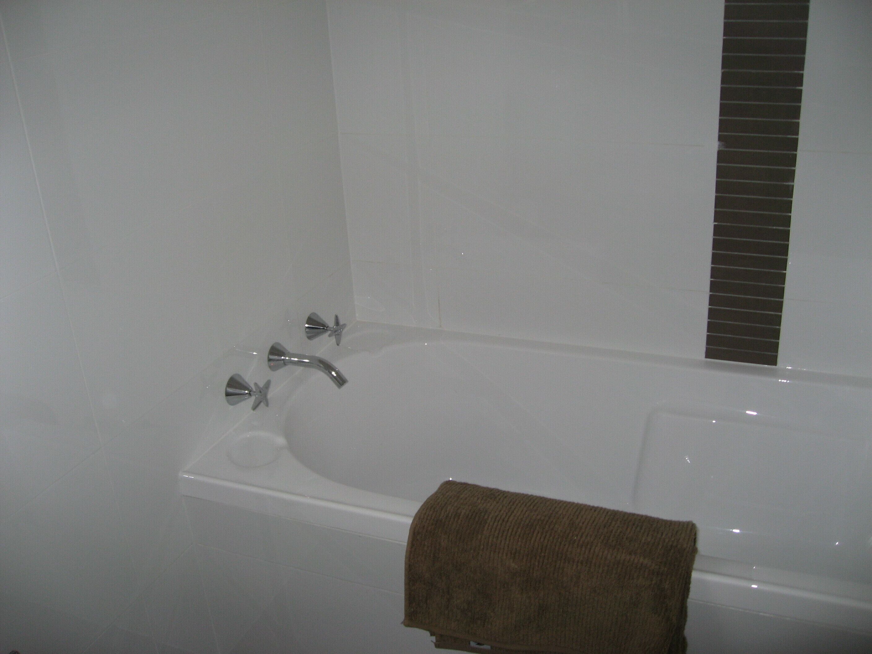 A bathtub with two faucets and a towel.