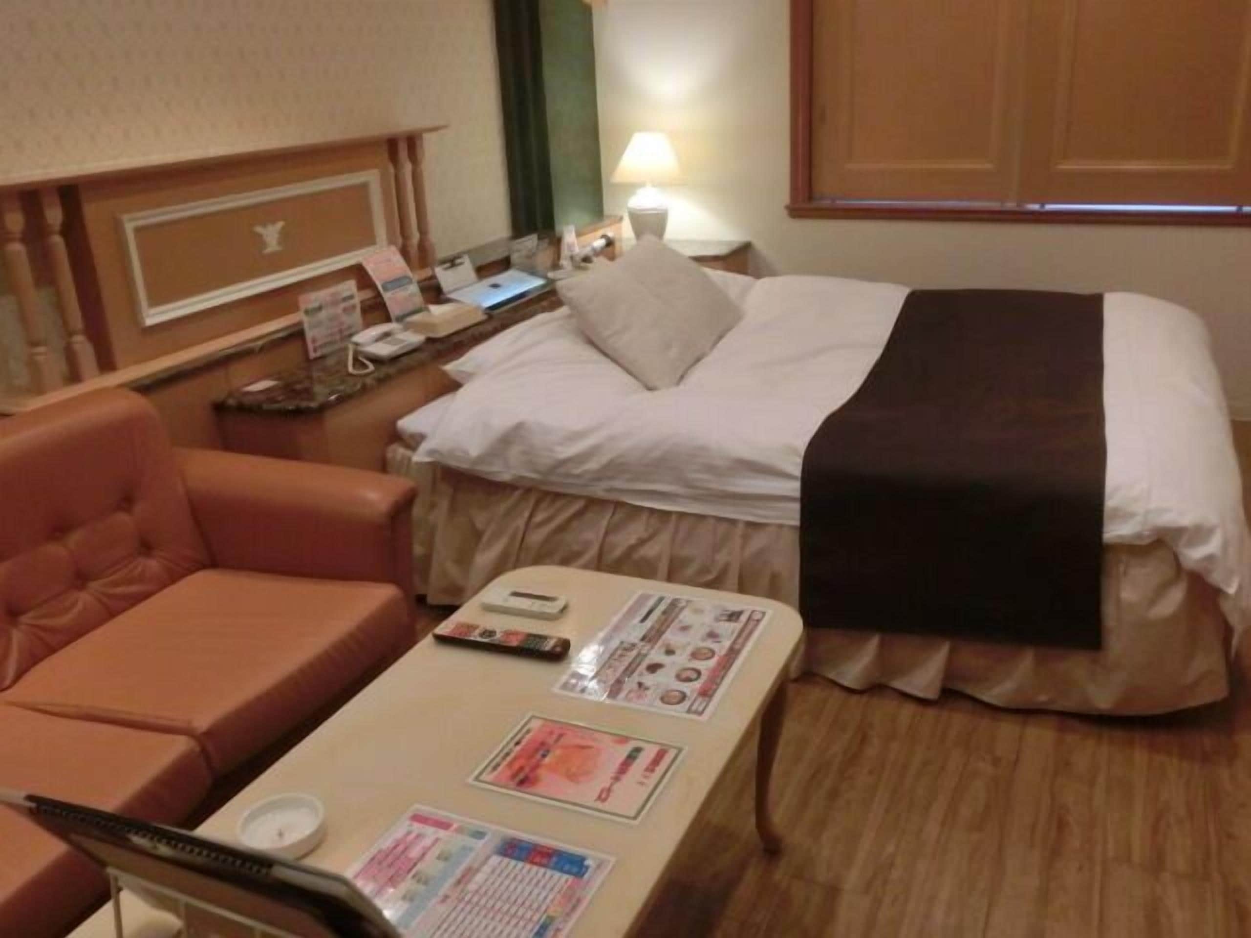 Habitación de hotel con cama, escritorio, silla y mesita de noche.