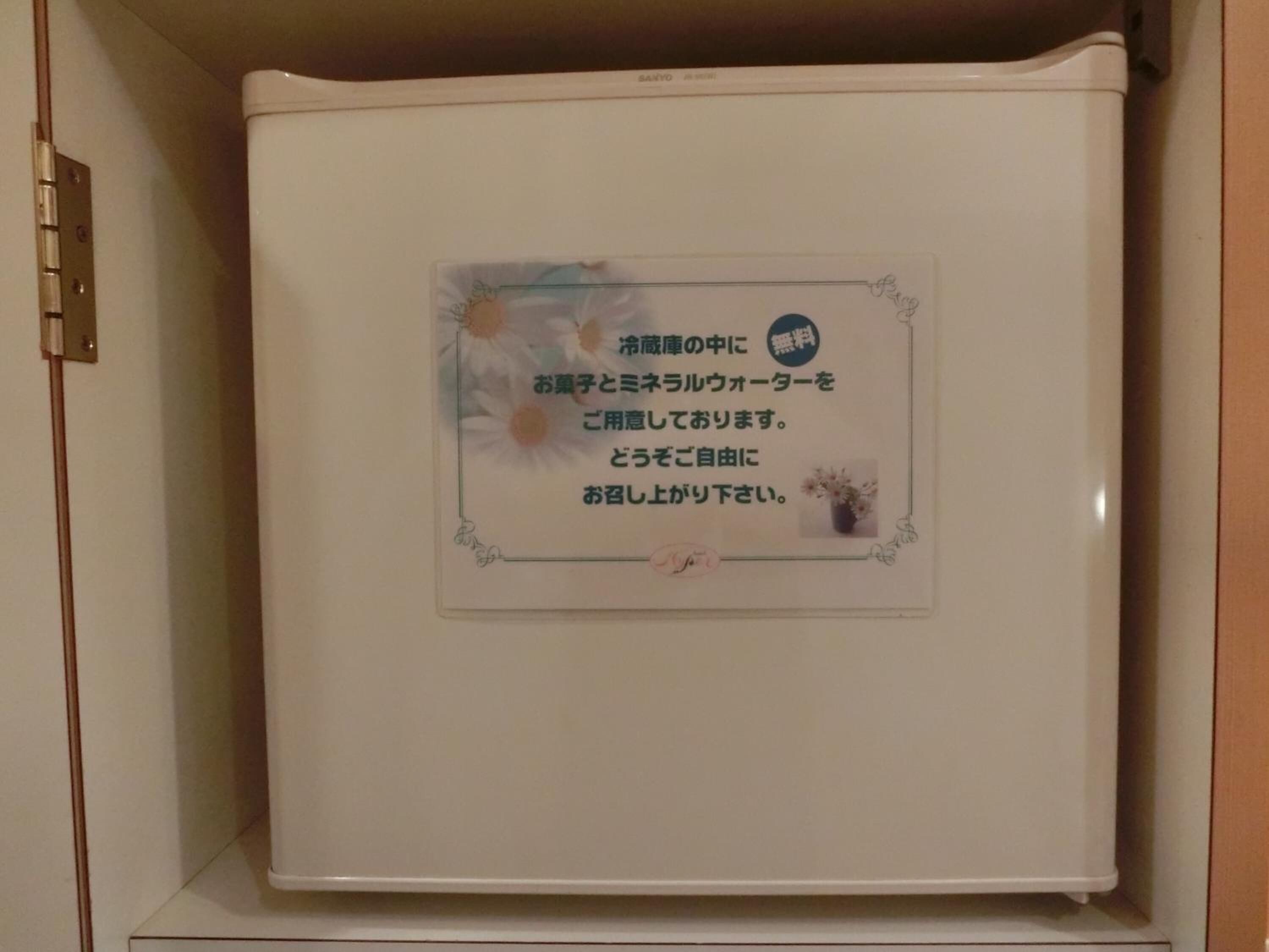 A white refrigerator with a sticker containing Japanese text.