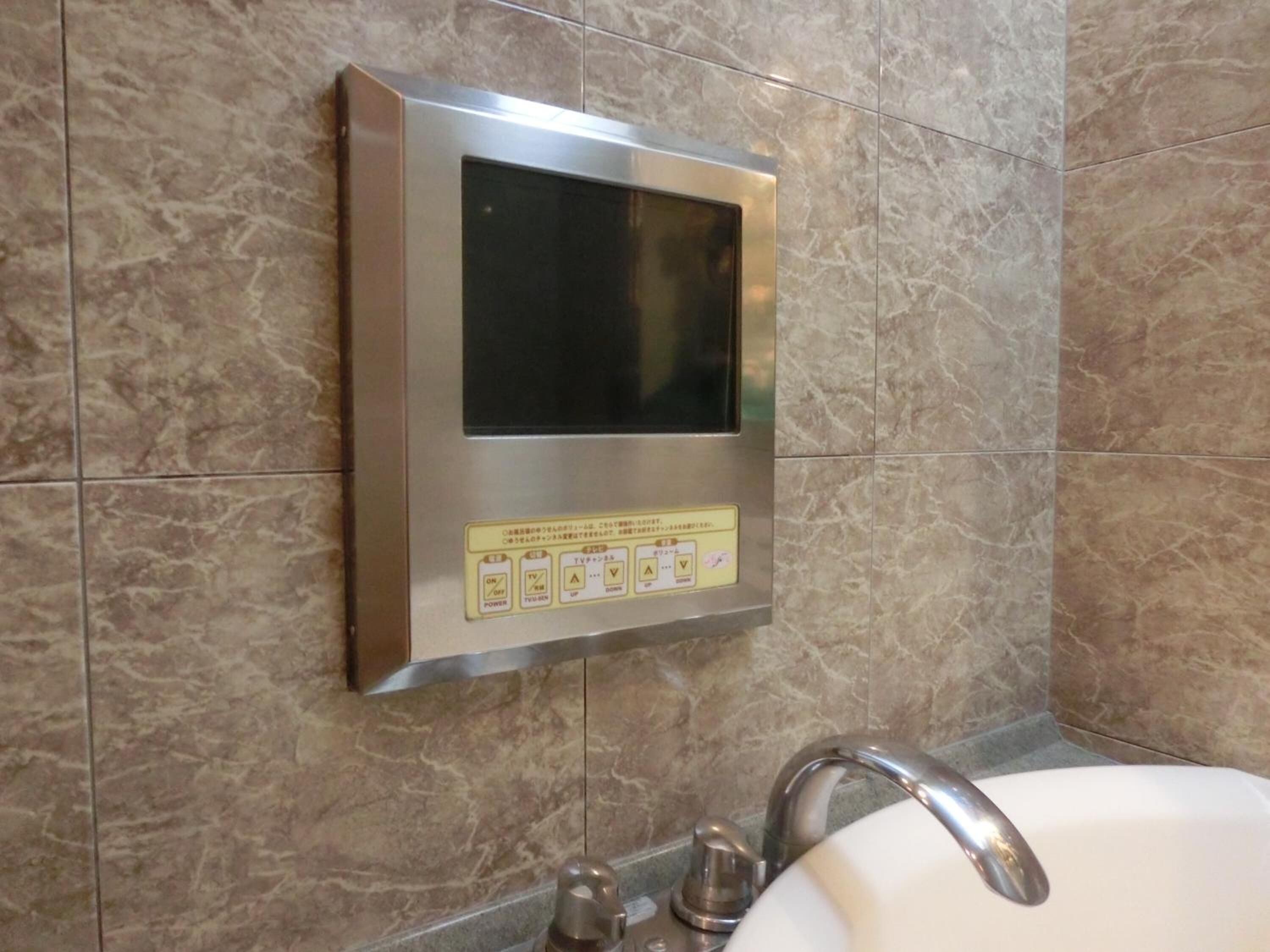Un baño con panel digital integrado sobre un lavabo, un espejo y un grifo.