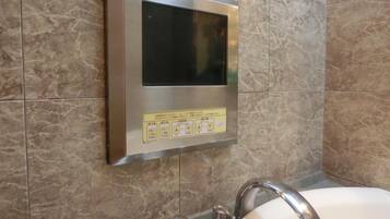 Un baño con panel digital integrado sobre un lavabo, un espejo y un grifo.