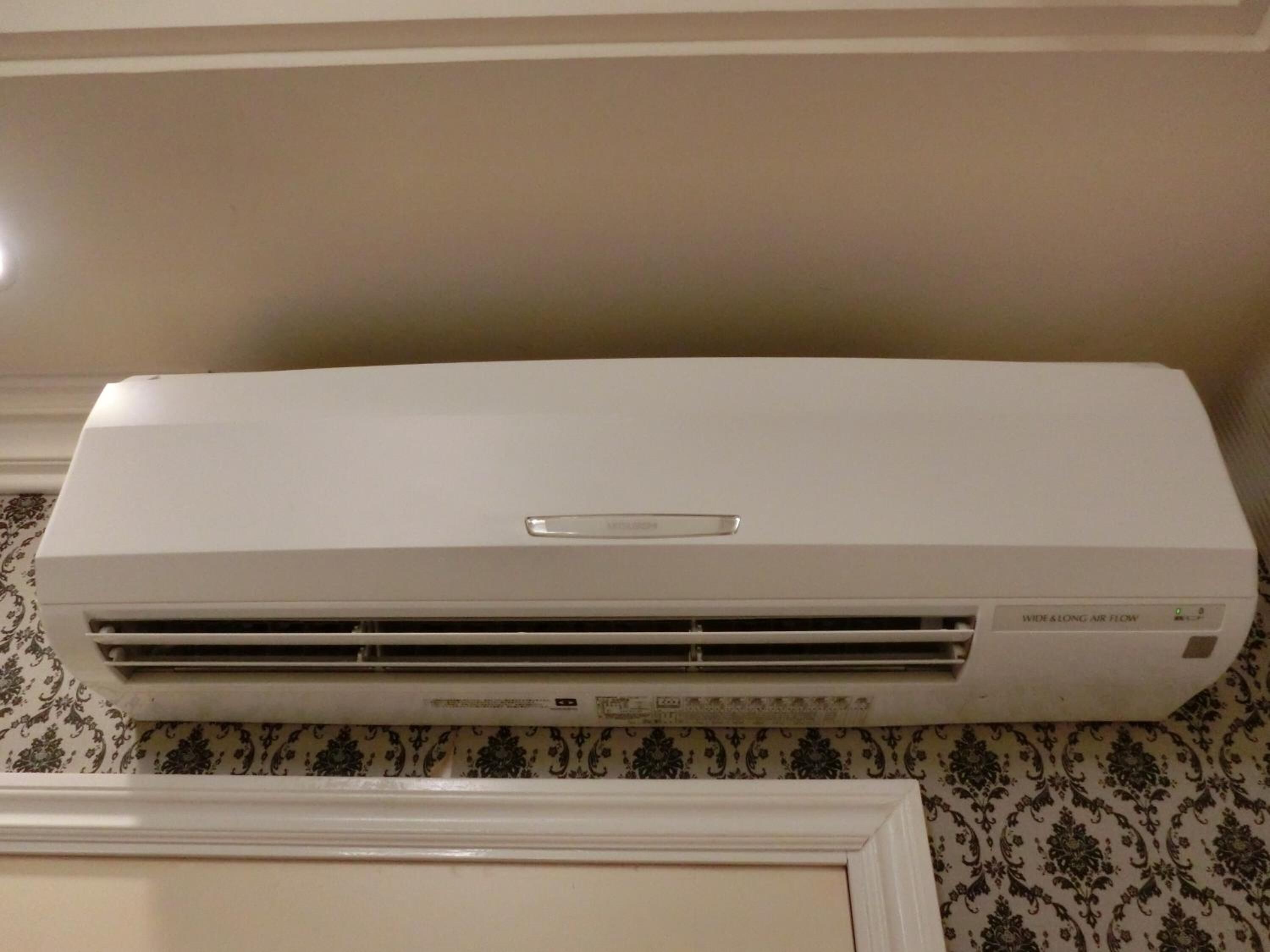 A white air conditioning unit with a control panel and a label indicating 'Wide & Long Air Flow'.