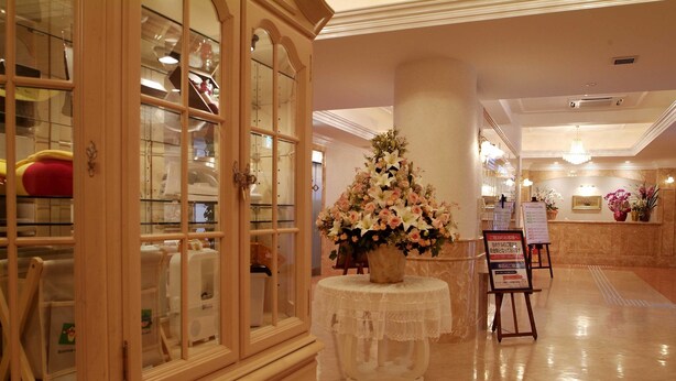 Un hall d’hôtel avec un meuble en bois, une table blanche agrémentée d’un arrangement floral et un comptoir d’accueil.