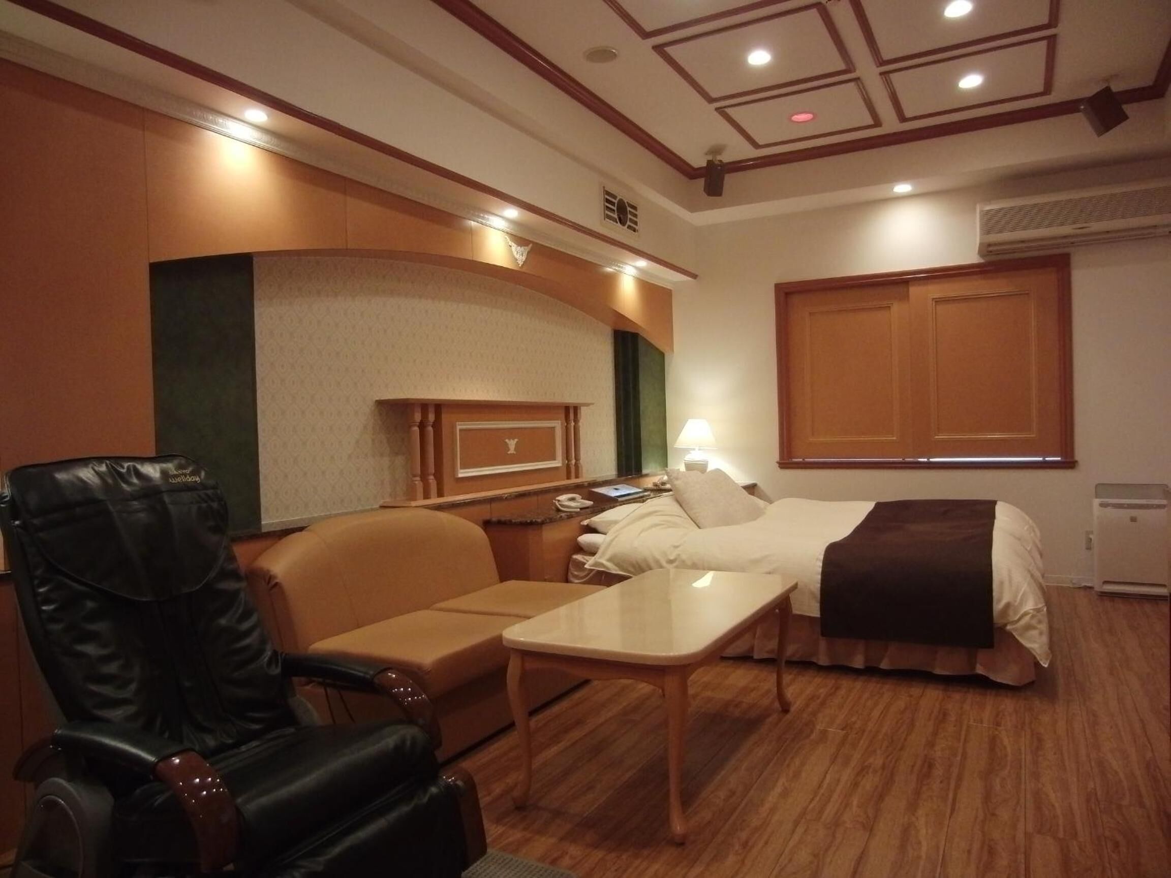 A hotel room with a bed, a desk, a leather chair, and a reception desk.