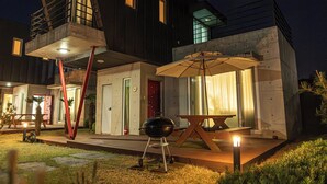 Ein modernes Haus mit außergewöhnlichem architektonischen Design, das einen großzügigen Grillbereich und eine weitläufige Terrasse bietet.