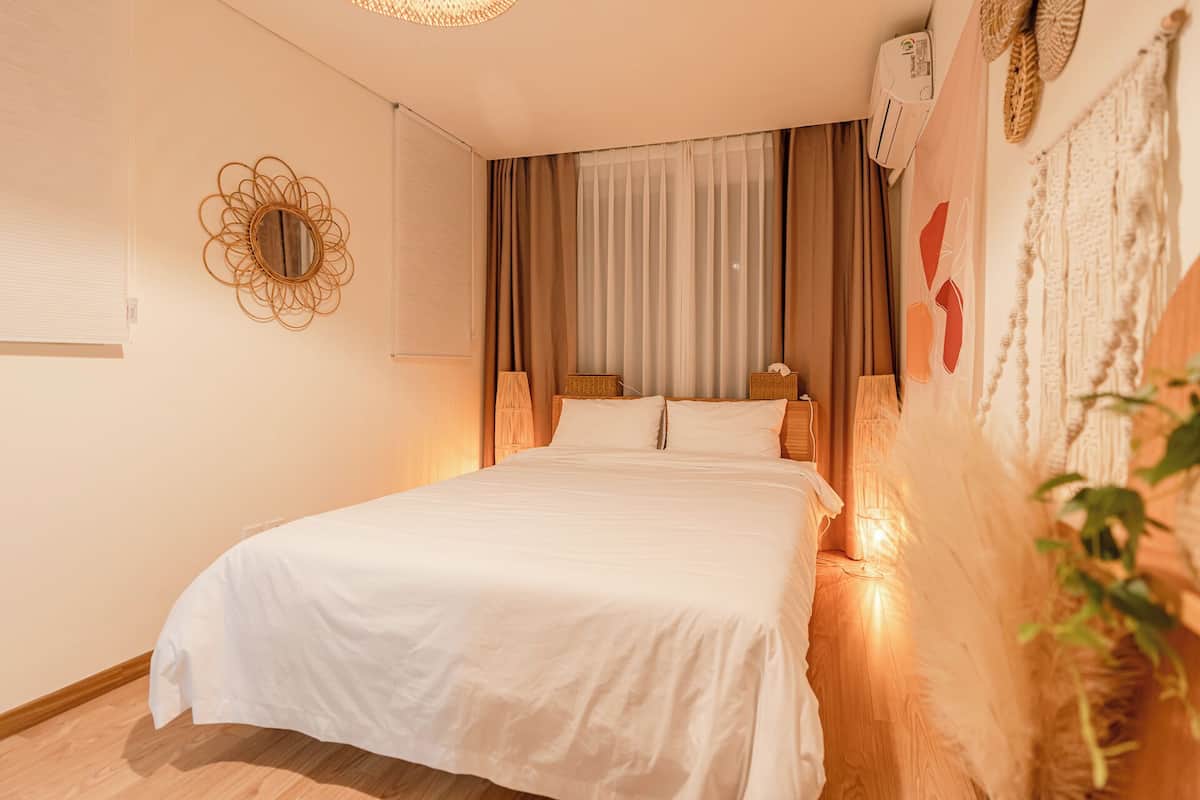 Un dormitorio ordenado con una cama grande, un espejo en la pared y un ventilador de techo.