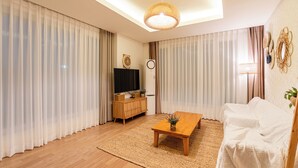 Ein modernes Wohnzimmer mit Couch, Fernseher auf Holzschrank und Couchtisch.