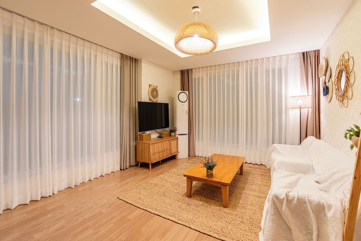 Una sala moderna con una mesa de centro de madera, un sofá y un televisor sobre un mueble de madera.