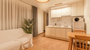Eine moderne Küche mit weißen Schränken, einem eingebauten Backofen und einem Essbereich mit Holztisch und -stühlen.