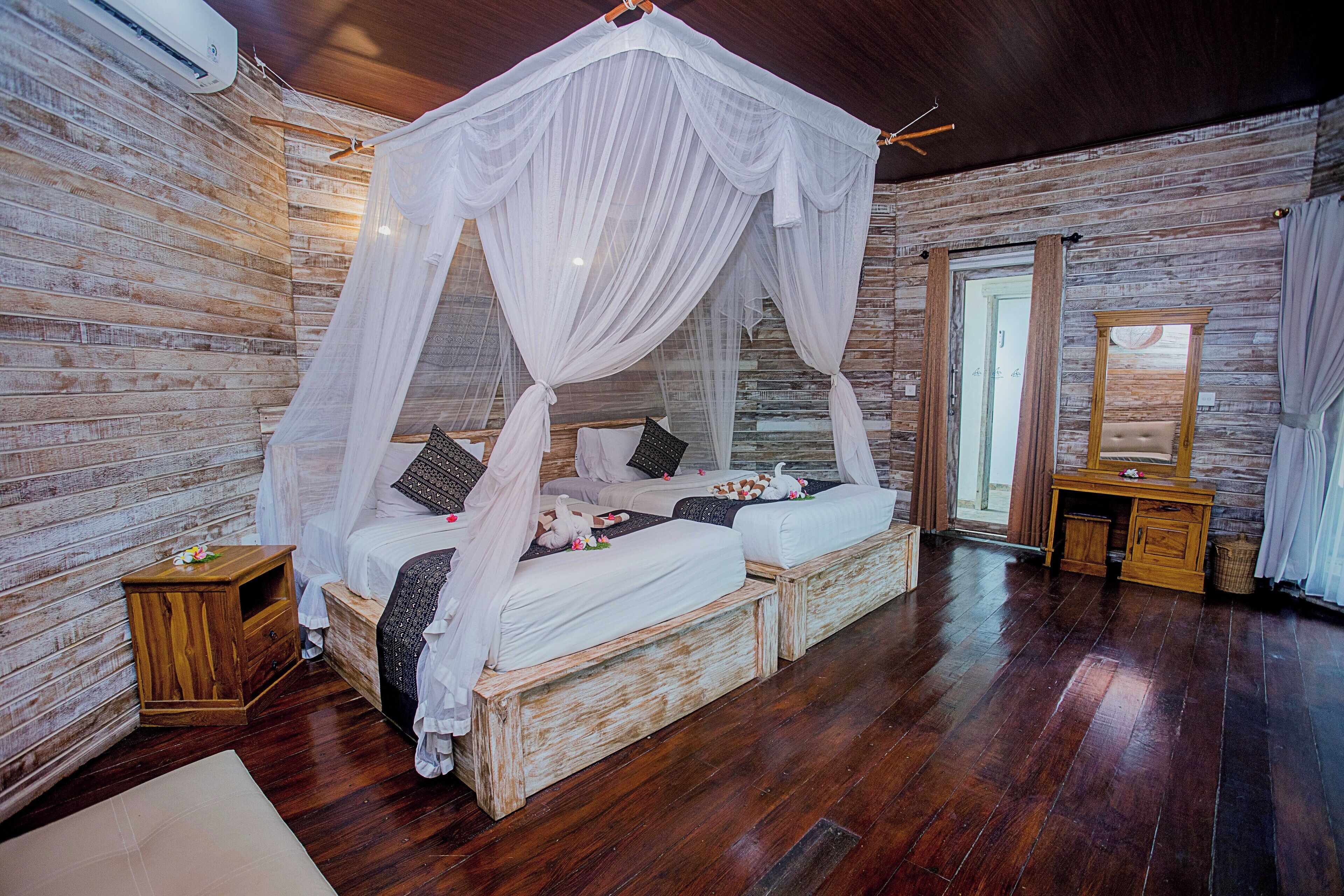 A bedroom with a canopy bed, wooden walls, and a wooden desk.