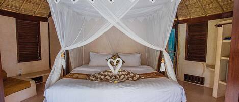A bed with a canopy, pillows, and a decorative swan design on the bedspread.