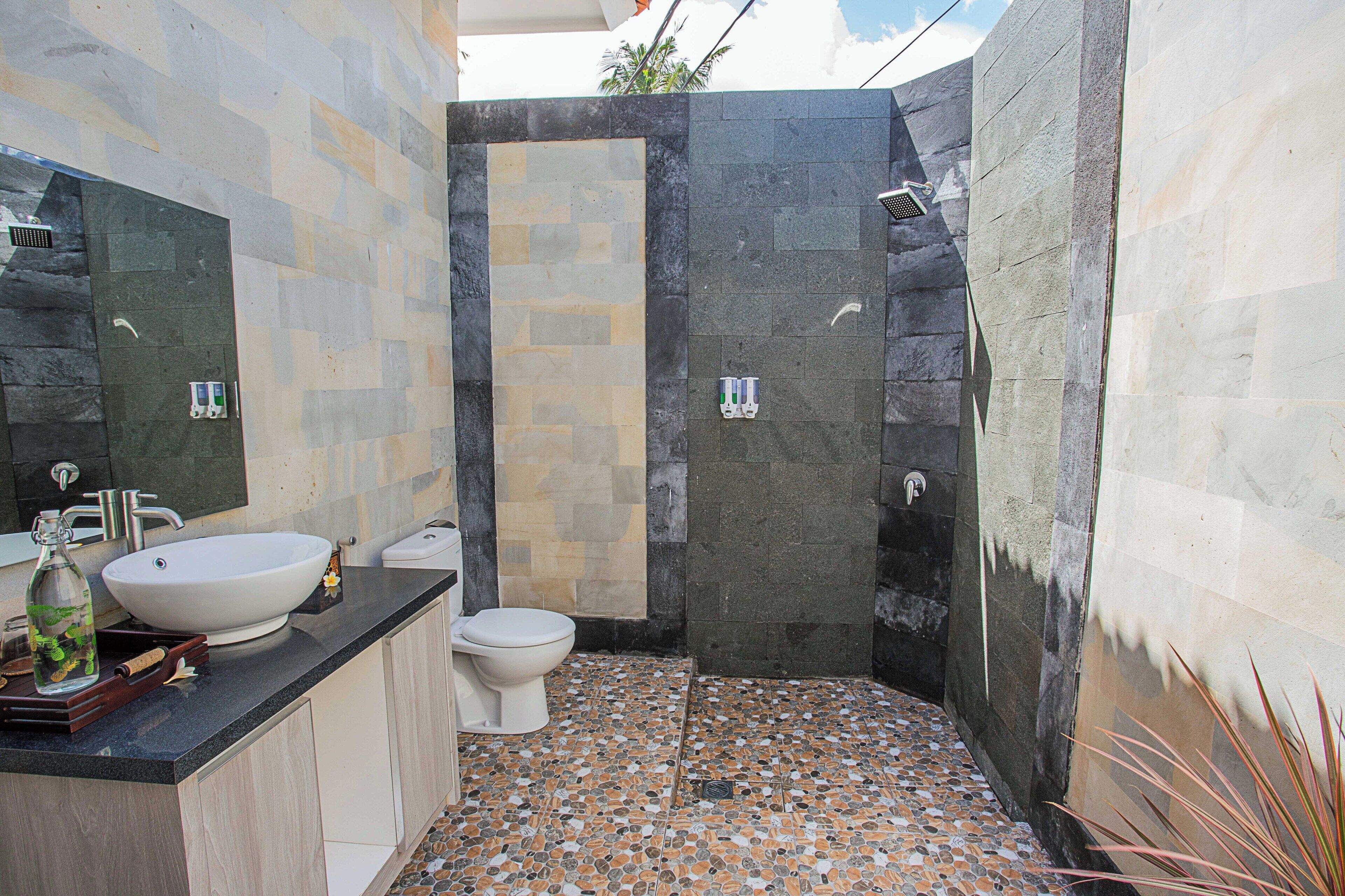A bathroom with a stone mosaic floor, a white sink, and a toilet.