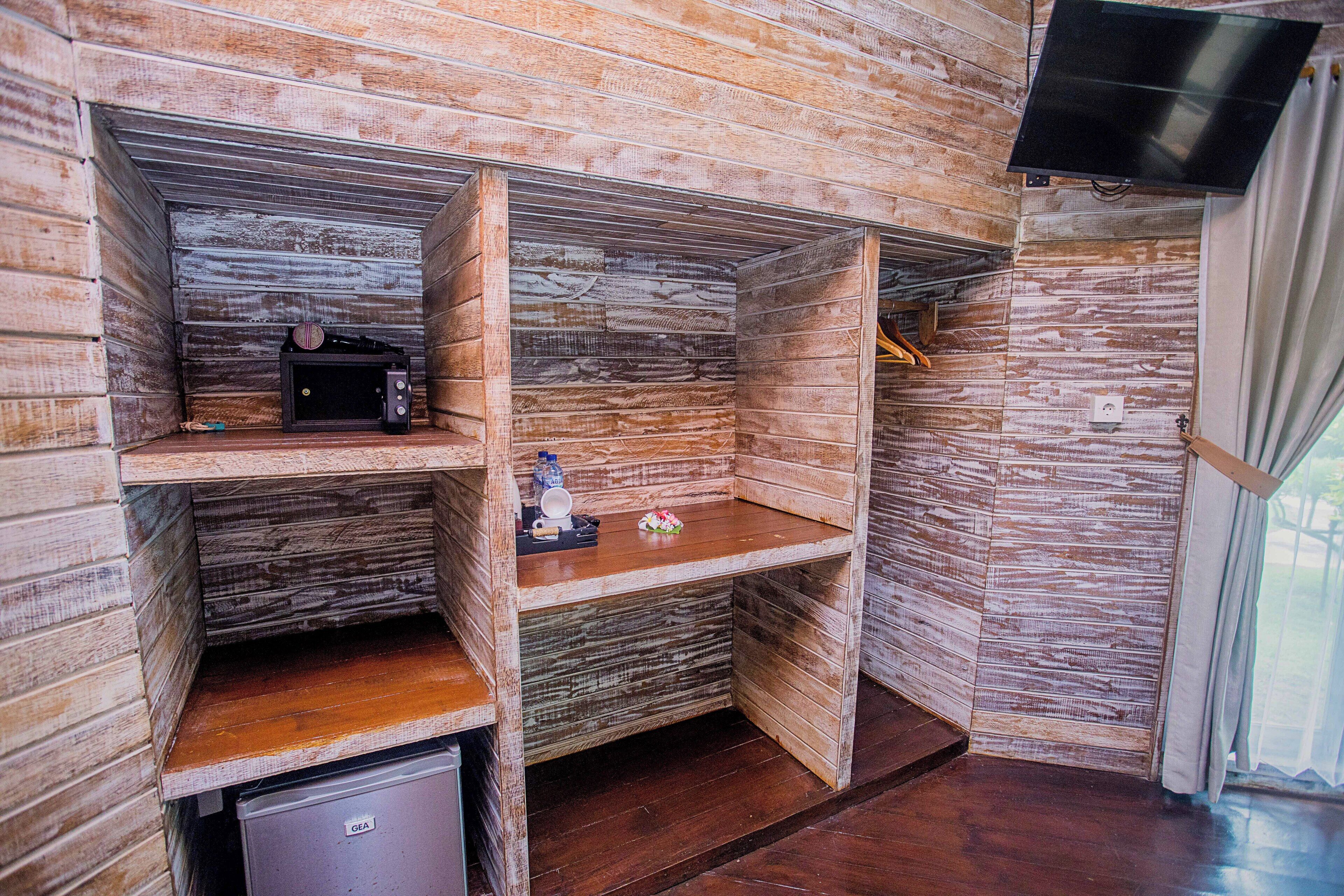 A compact room with wooden walls and a built-in microwave shelf.