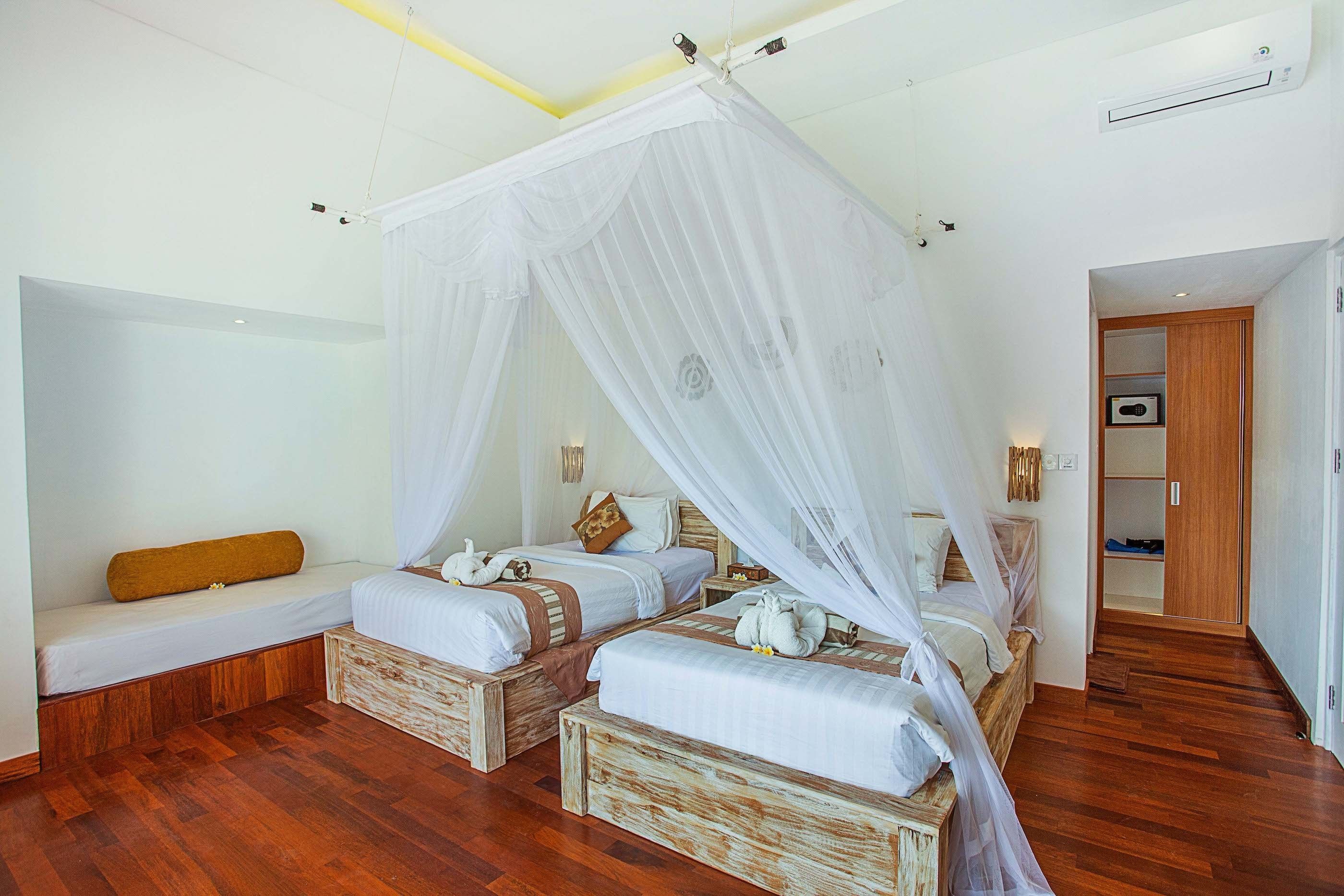 A bedroom with two beds, a bench, and a wardrobe.