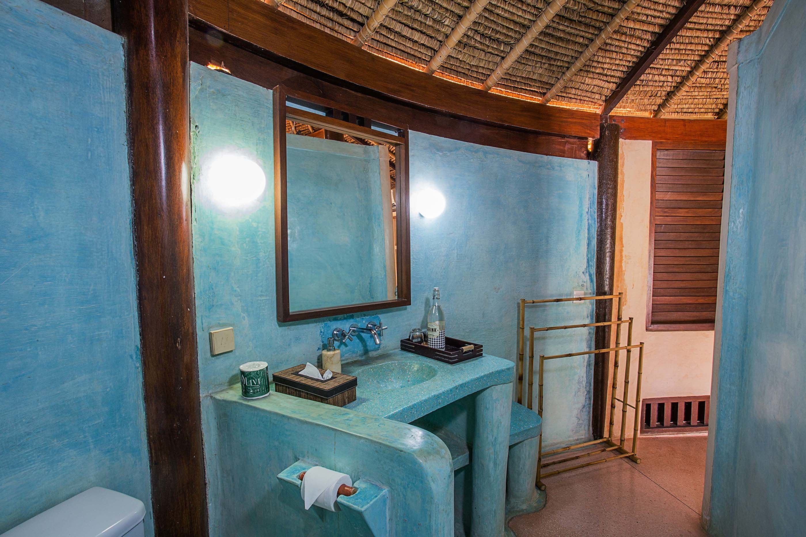Een badkamer met een blauwe wastafel, een spiegel en een toilet.