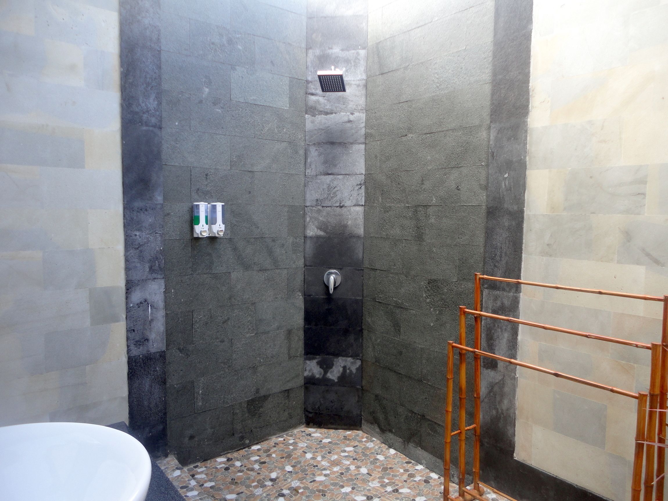 A small, tiled shower area with a toilet and a bamboo shower caddy.