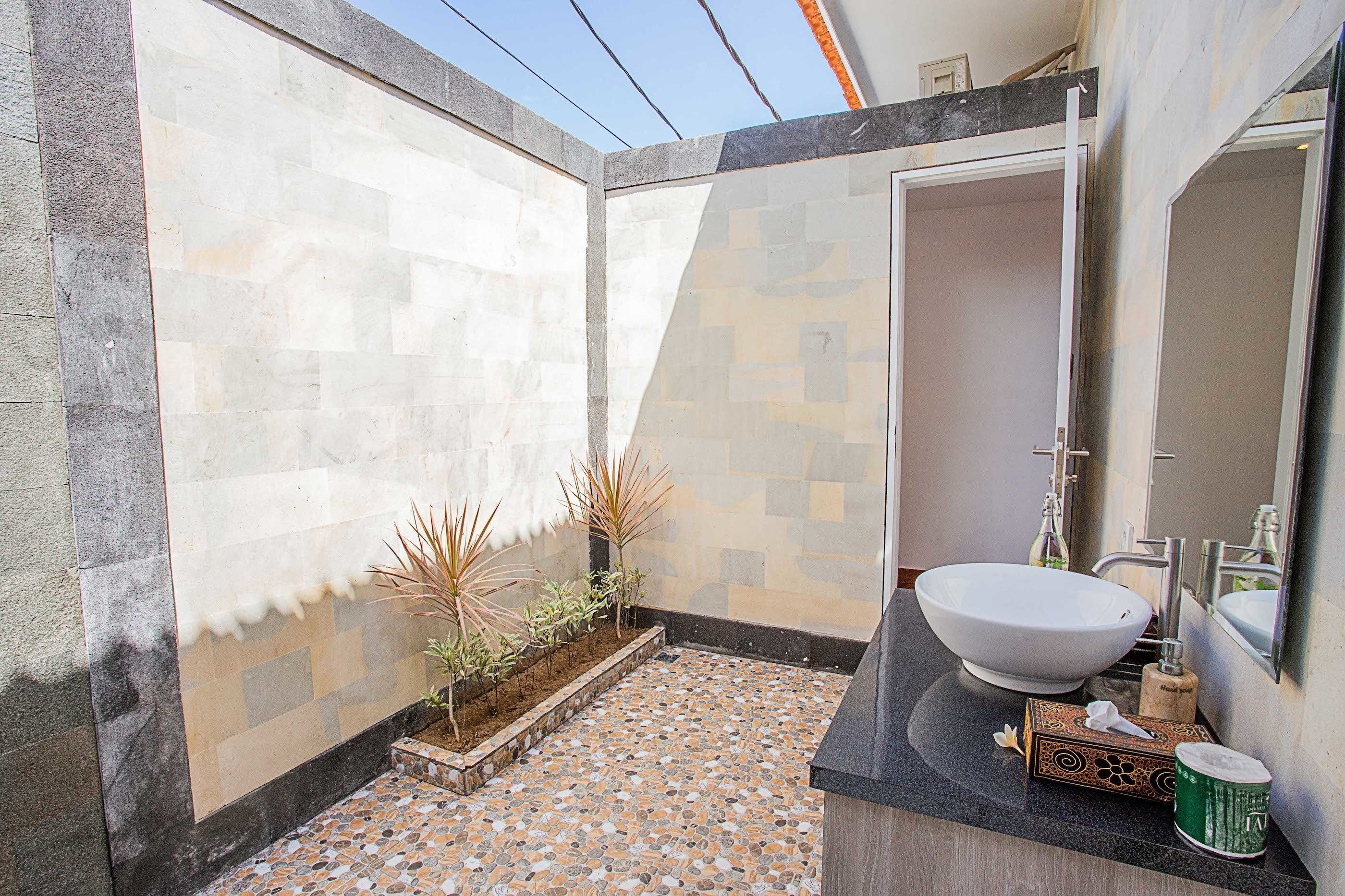 Un baño con un lavamanos grande de color blanco, un espejo y suelo de baldosas.