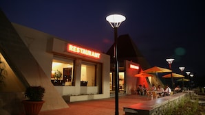 A restaurant with a modern design, outdoor seating, and illuminated signage. - Sentosa Resorts and Water Park (Pune)