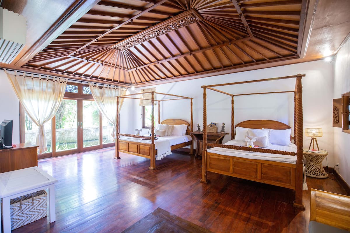 Habitación con cama con dosel, techo de madera y ventanas amplias.