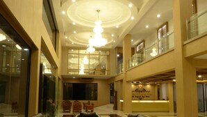 A spacious lobby with leather sofas, a reception desk, and a chandelier. - The Impress Nan Hotel (Nan)