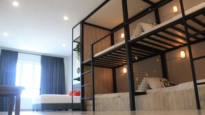 Une chambre d’hôtel moderne avec un lit superposé, un bureau et une grande fenêtre avec des rideaux.