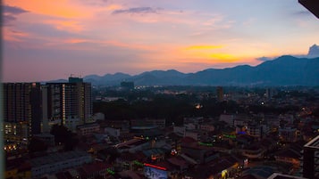 A cityscape at dusk with buildings and mountains in the background.