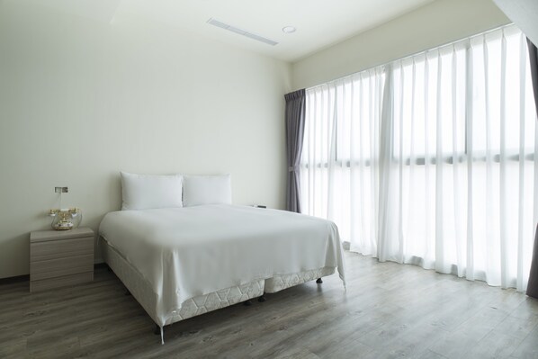 Un dormitorio con cama, mesita de noche y ventana con cortinas.