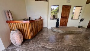 A reception area with a wooden reception desk, a woven basket, and a statue. - Bamboo Paradise Beach Resort (Argao)