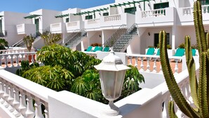 A white building with balconies, green plants, and cacti. - Apartamentos Tisalaya (Tías)