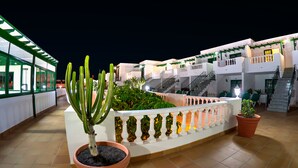 A hotel courtyard with potted cacti, a white railing, and a staircase leading to upper floors. - Apartamentos Tisalaya (Tías)