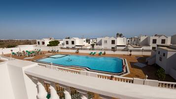 A rooftop swimming pool with lounge chairs and a view of white buildings.