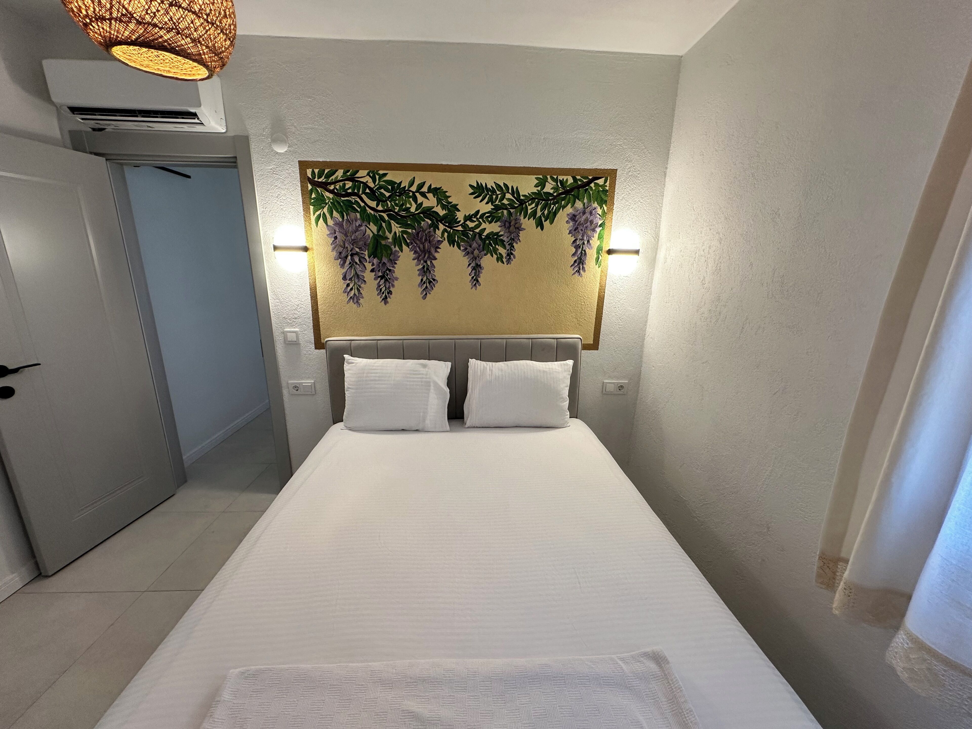 A hotel room with a bed, a wall-mounted artwork, and a door.