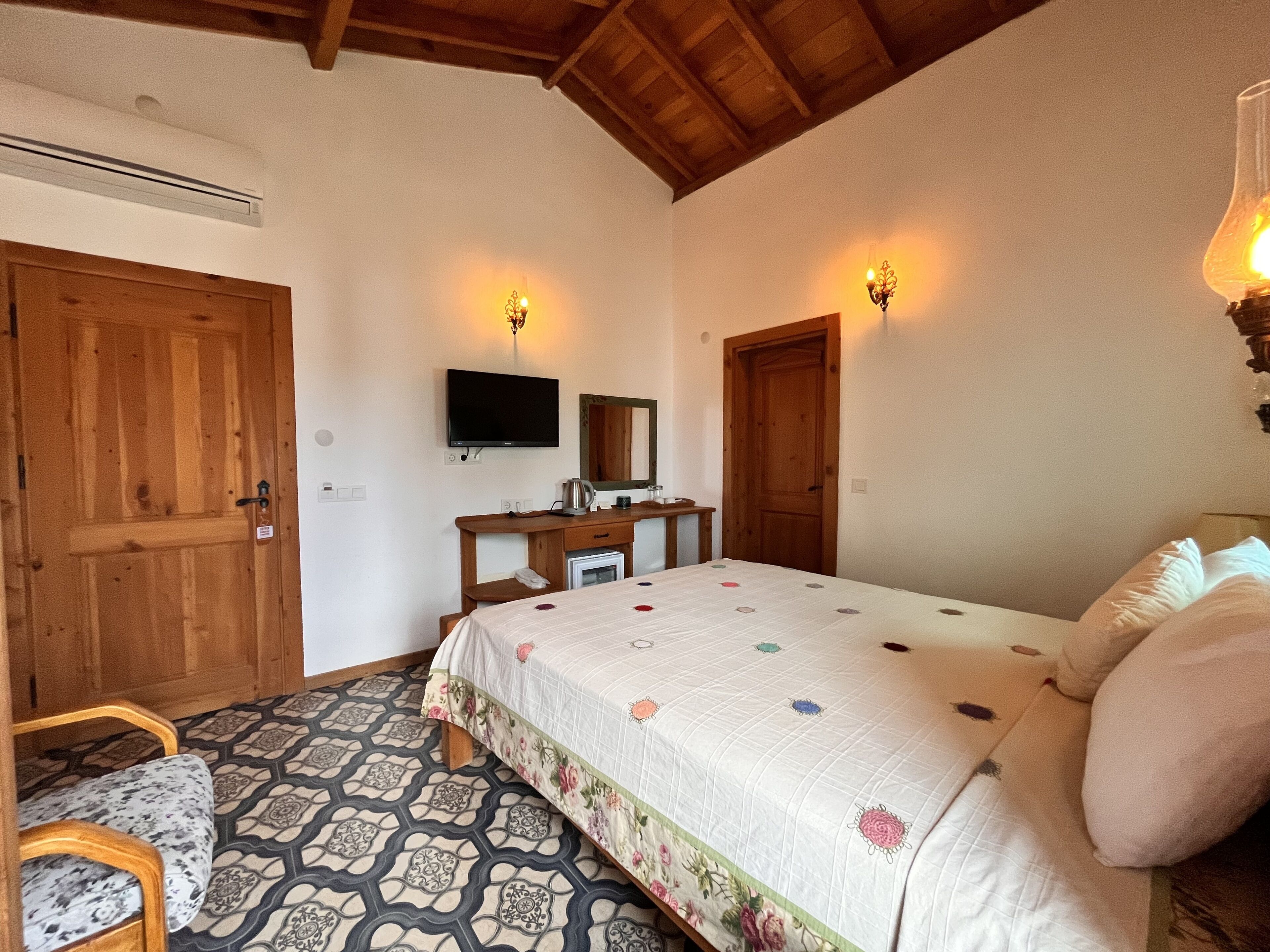Un dormitorio con una cama, un escritorio, un televisor y una puerta de madera.