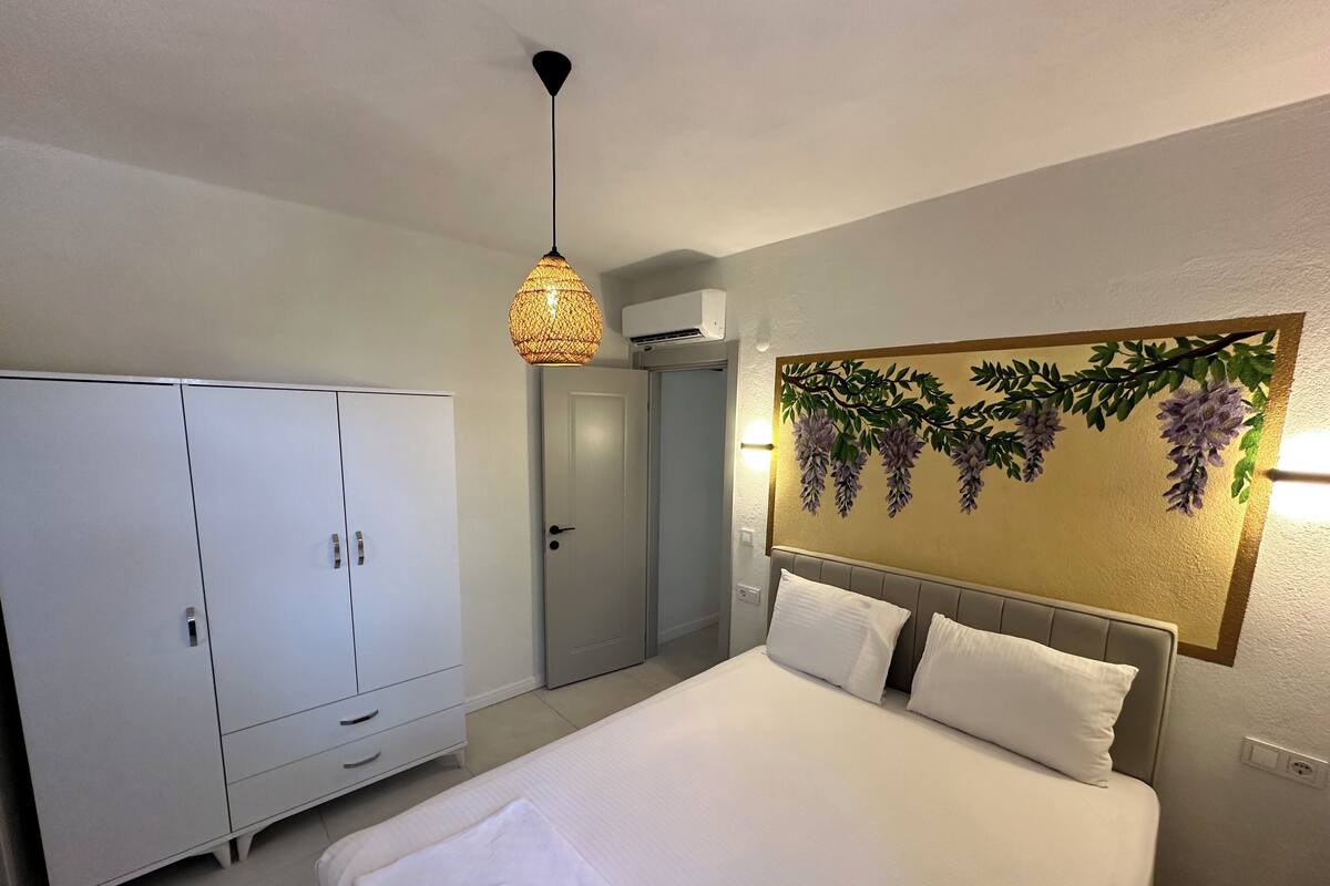 A bedroom with a bed, wardrobe, and a wall-mounted light fixture.