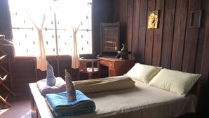 Quarto com cama, escrivaninha e cadeira. Há uma janela com cortinas e um quadro na parede.