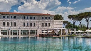 Un bâtiment en pierre avec une piscine devant.