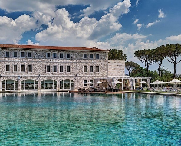 A stone building with a pool in front.