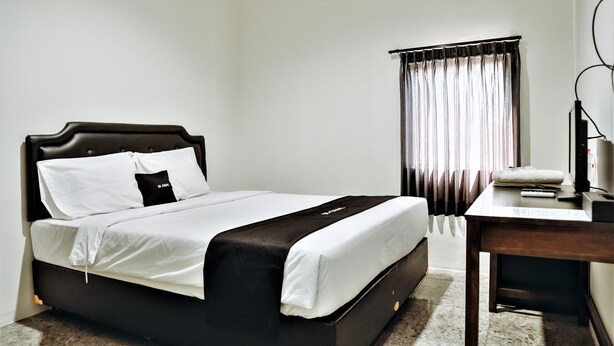 Una habitación de hotel con cama, escritorio y ventana con cortinas.