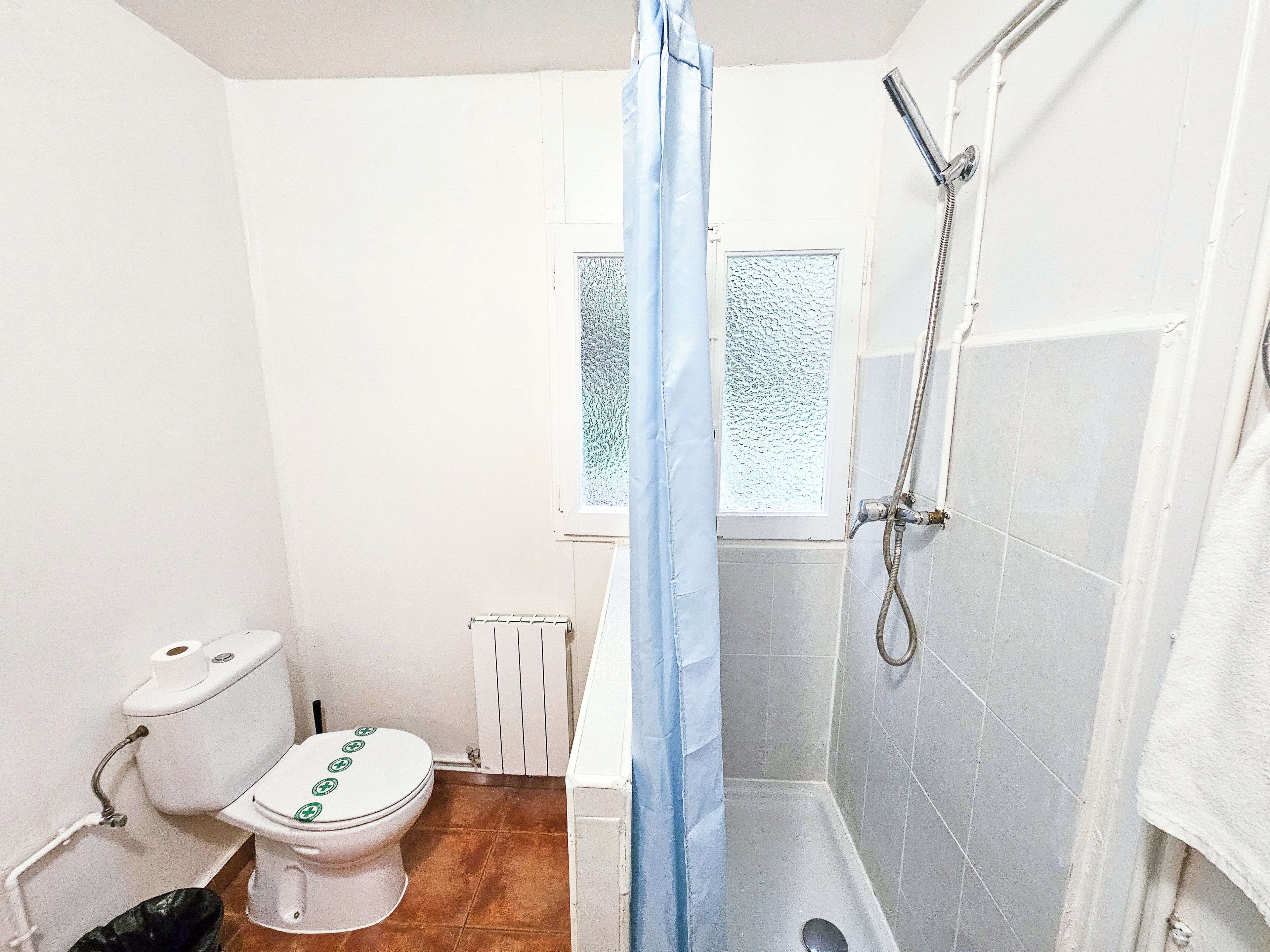 Ein kleines Badezimmer mit Toilette, Dusche und Fenster.